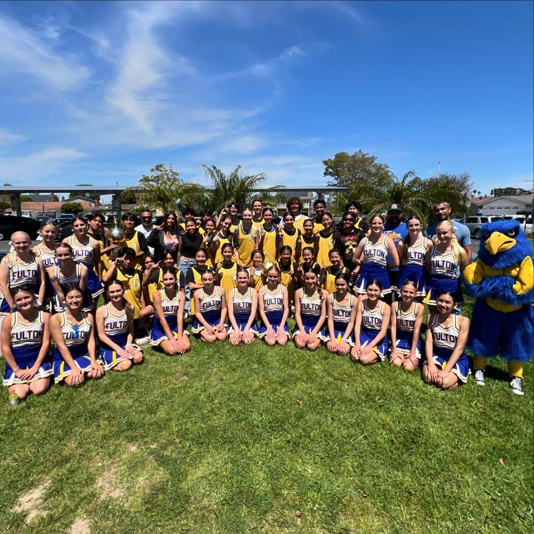 Cheerleaders, women&rsquo;s basketball team, and men&rsquo;s basketball team posing in a semi circle on a lawn who are students at Fulton Middle School