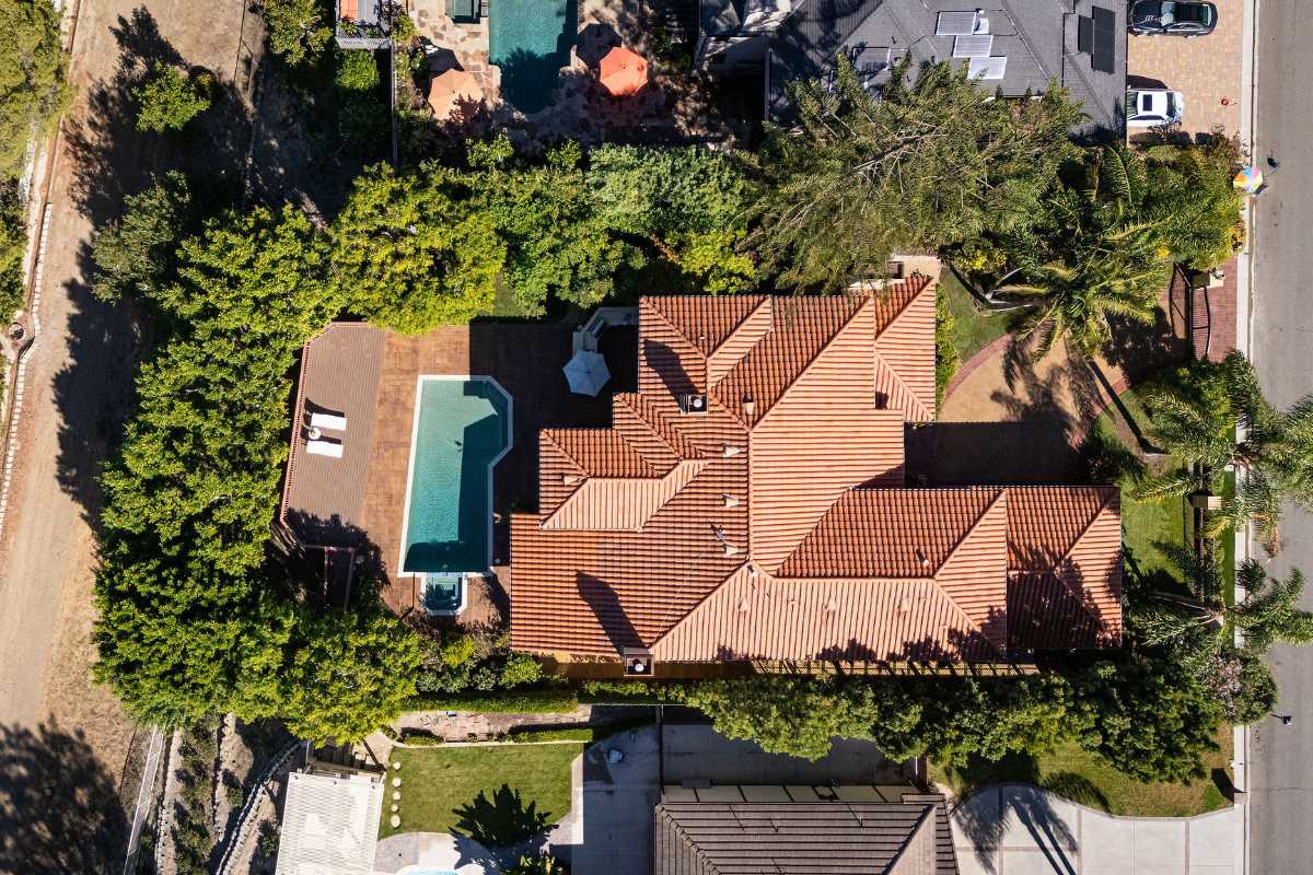 Aerial top-down drone photo of the Laguna Hills home, showing its roof, landscaping, and backyard pool, by top listing agents in Orange County, CA.