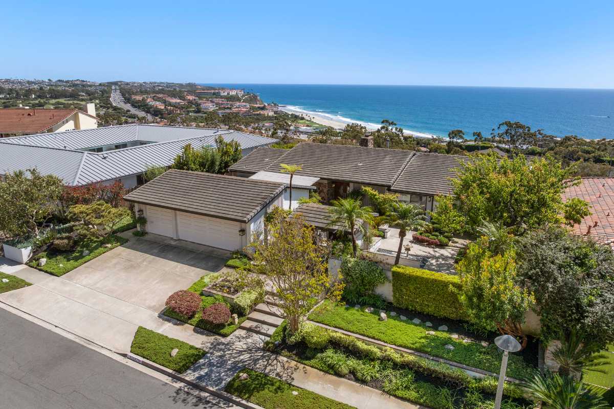 Dana Point luxury home exterior with landscaped front yard and the ocean in the background, in one of the best neighborhoods for homebuyers