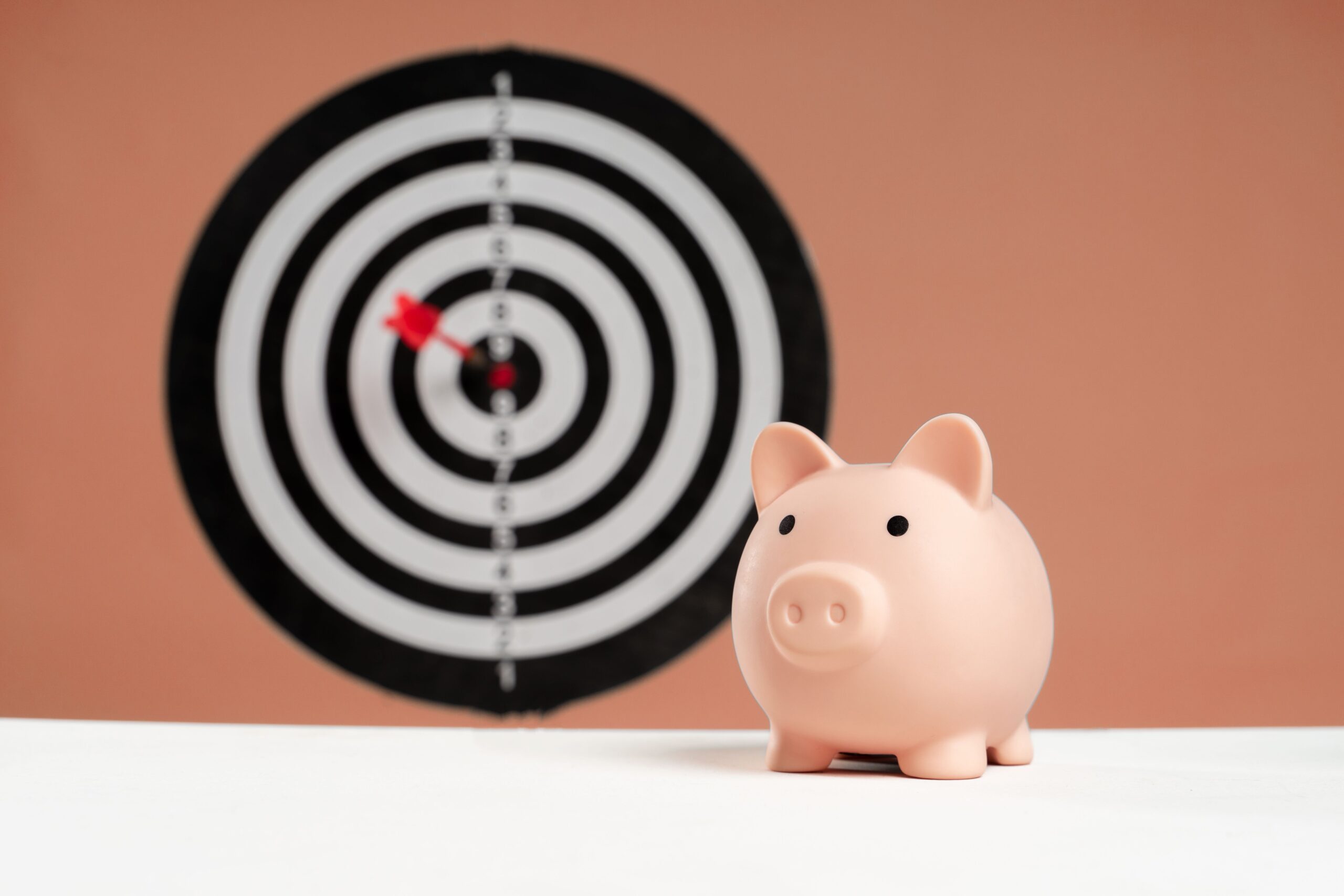 A piggy bank in front of an archery target bullseye, representing the concerns and questions to ask before you make an offer to buy a home in Orange County, CA